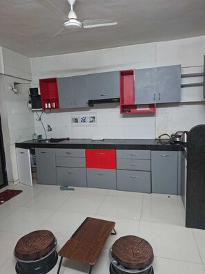 Une cuisine avec des meubles de couleur grise, un plan de travail rouge et un ventilateur de plafond.