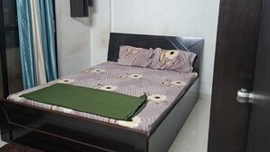 A bedroom with a bed, a ceiling fan, a door, and a window with curtains.