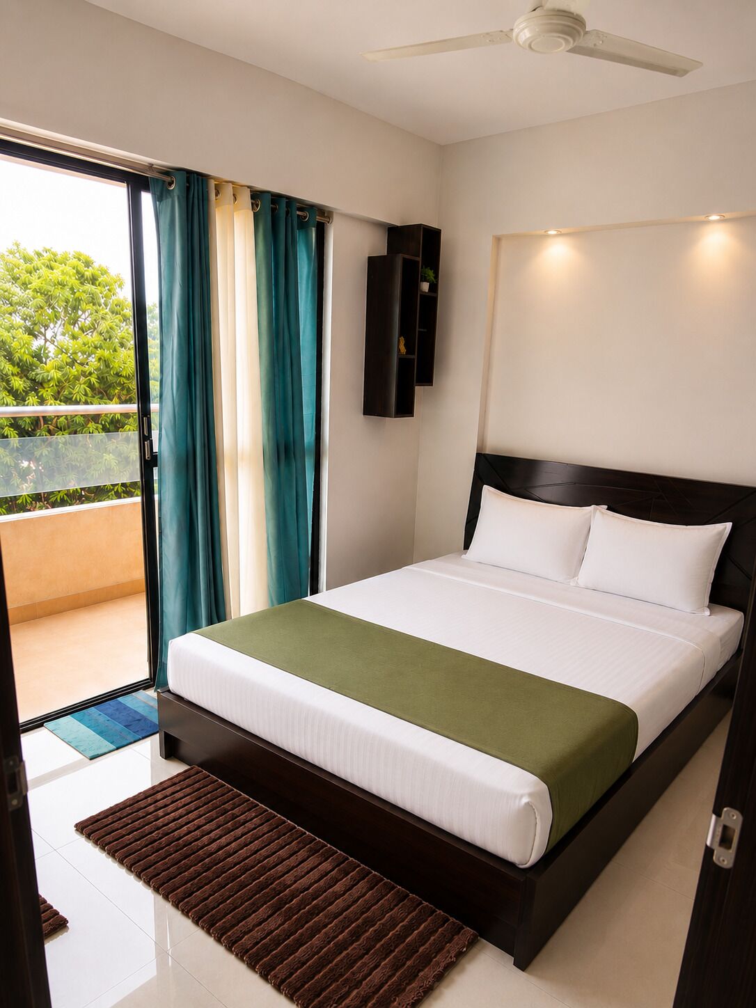 A hotel room with a bed, a ceiling fan, a view of the outdoors, and a sliding door.