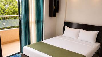 A hotel room with a bed, a ceiling fan, a view of the outdoors, and a sliding door.