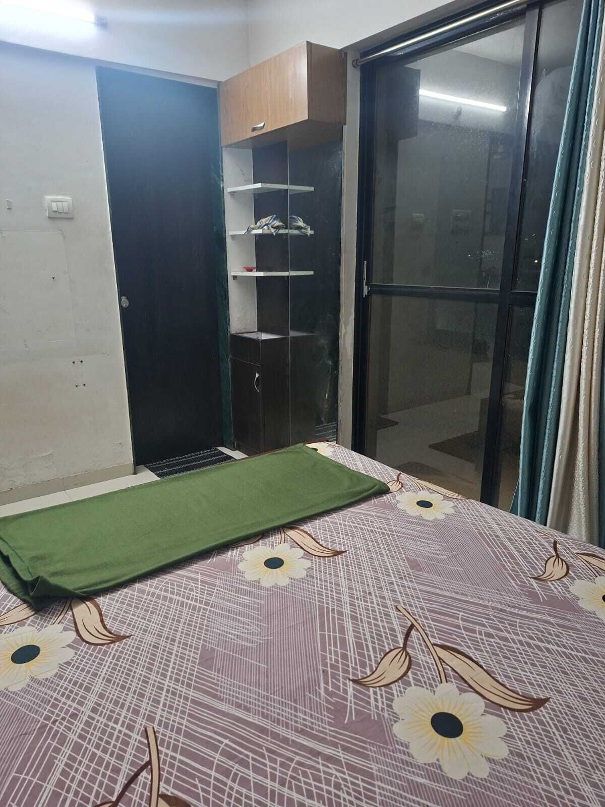 A bedroom with a bed, a wardrobe, and a sliding glass door.