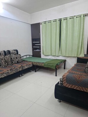 A room with a sofa set, a bed, a green curtain, and a wardrobe.