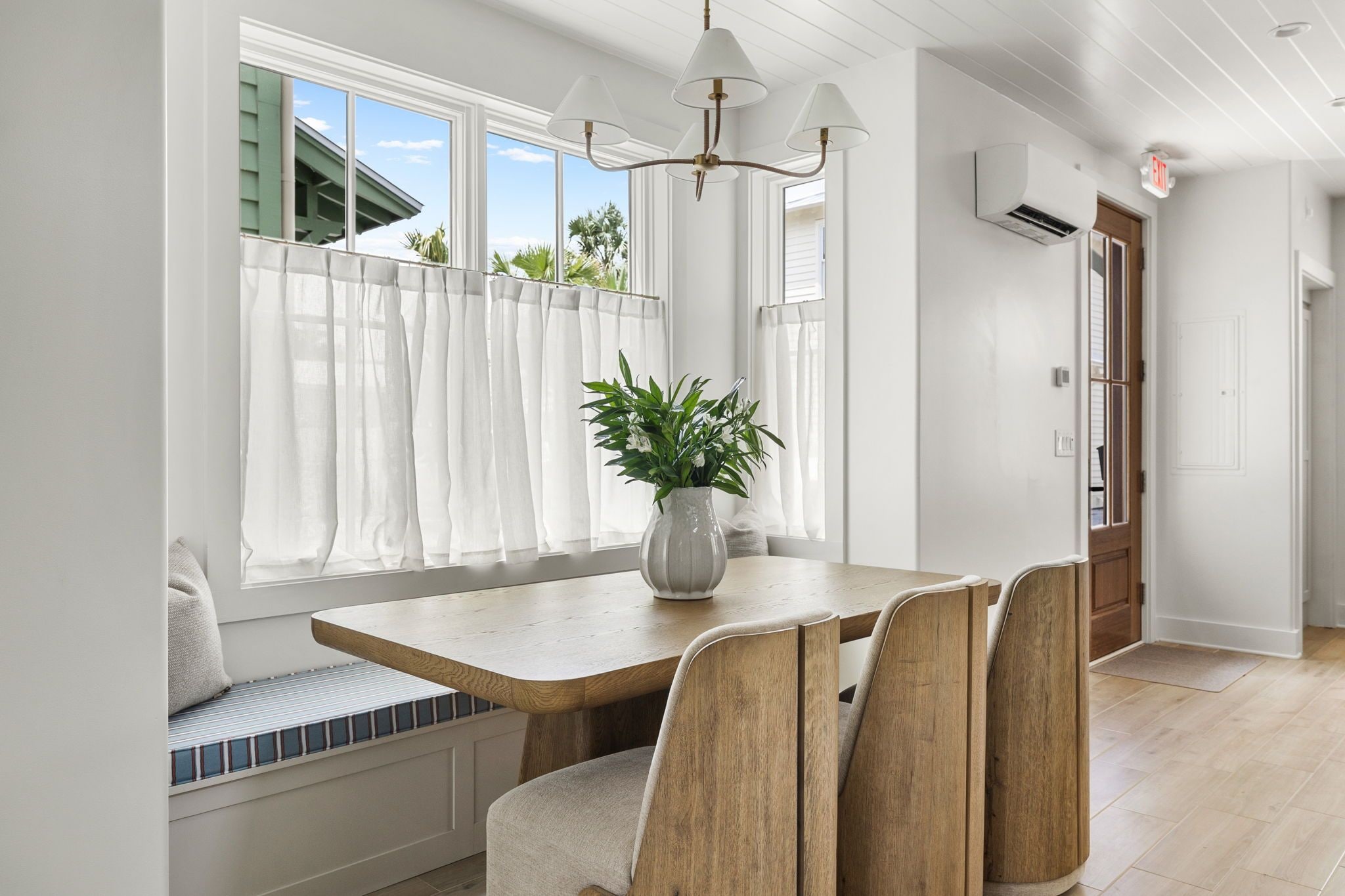 A dining area with a wooden table, cushioned bench seating, and a potted plant.