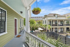 A balcony with a hanging plant, a pool, and a view of neighboring buildings. - Smalls Alley (Charleston)