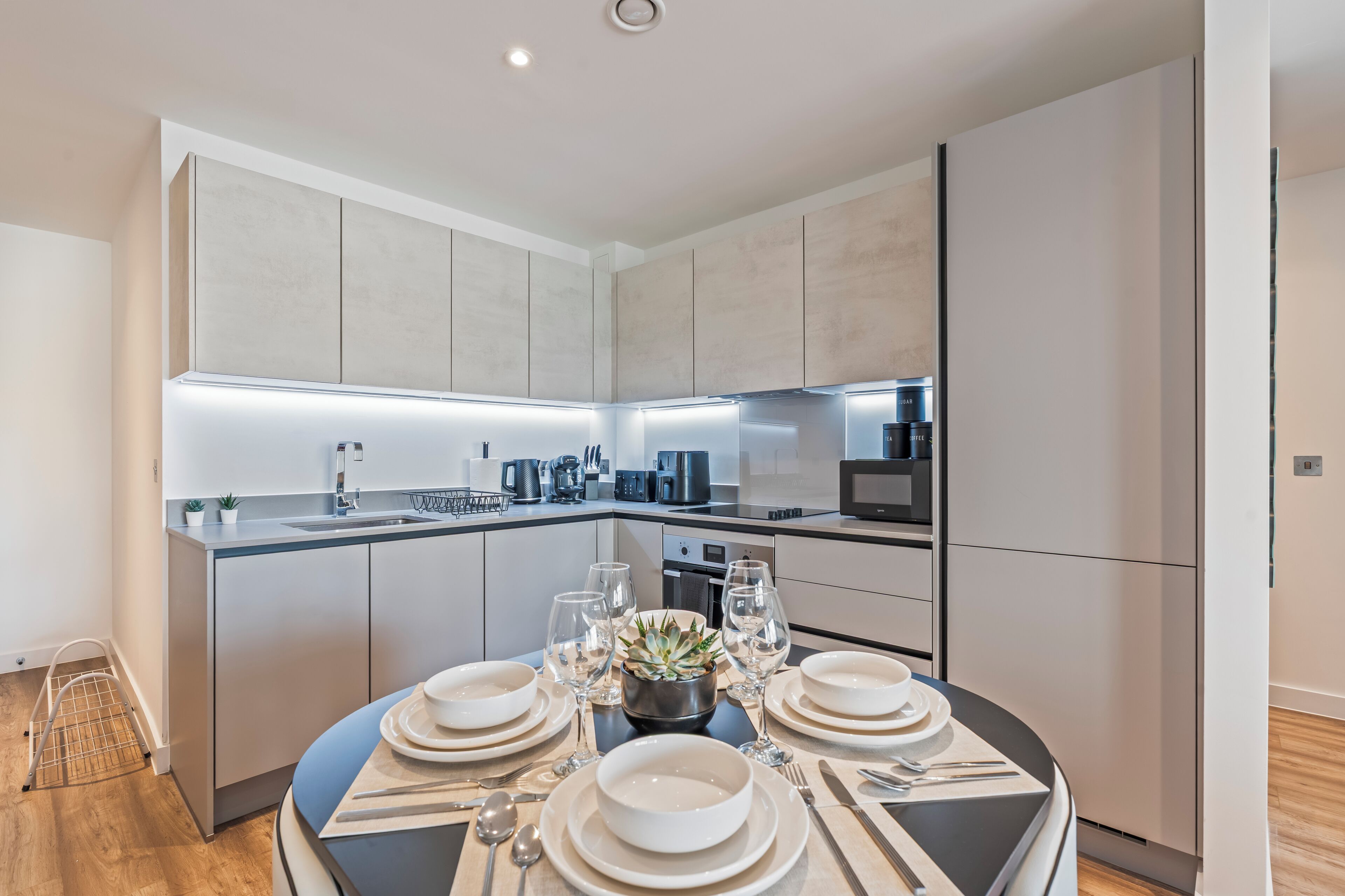 A modern kitchen with a central island, built-in appliances, and a dining area set for a meal.