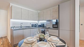 A modern kitchen with a central island, built-in appliances, and a dining area set for a meal.