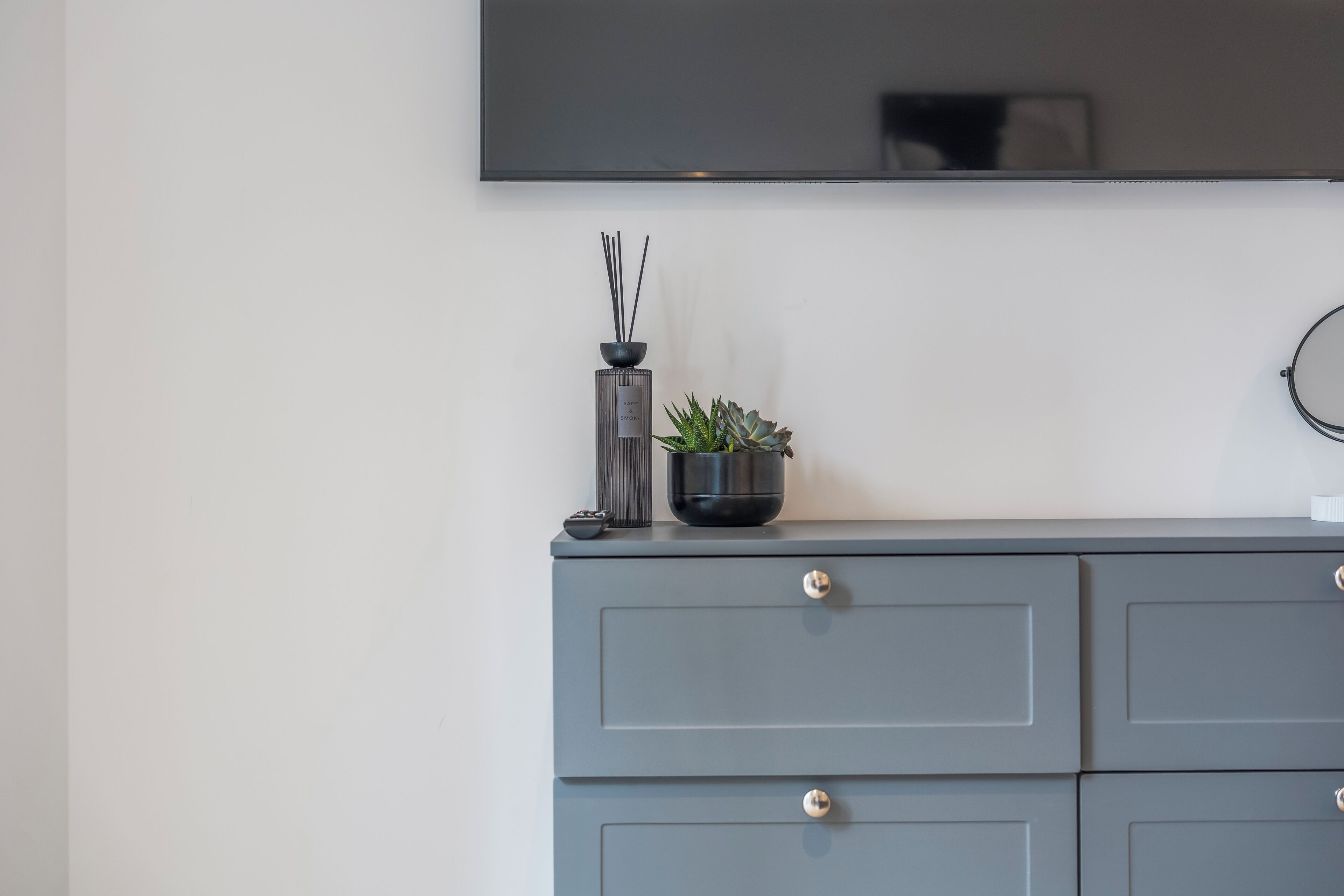 A grey dresser with a flat-screen TV mounted above it.