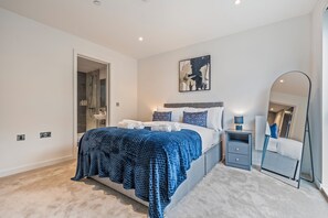Un dormitorio con cama, mesita de noche, espejo y zona de ducha.