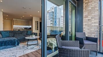 A modern living room with a sofa, a coffee table, and a balcony with wicker furniture.