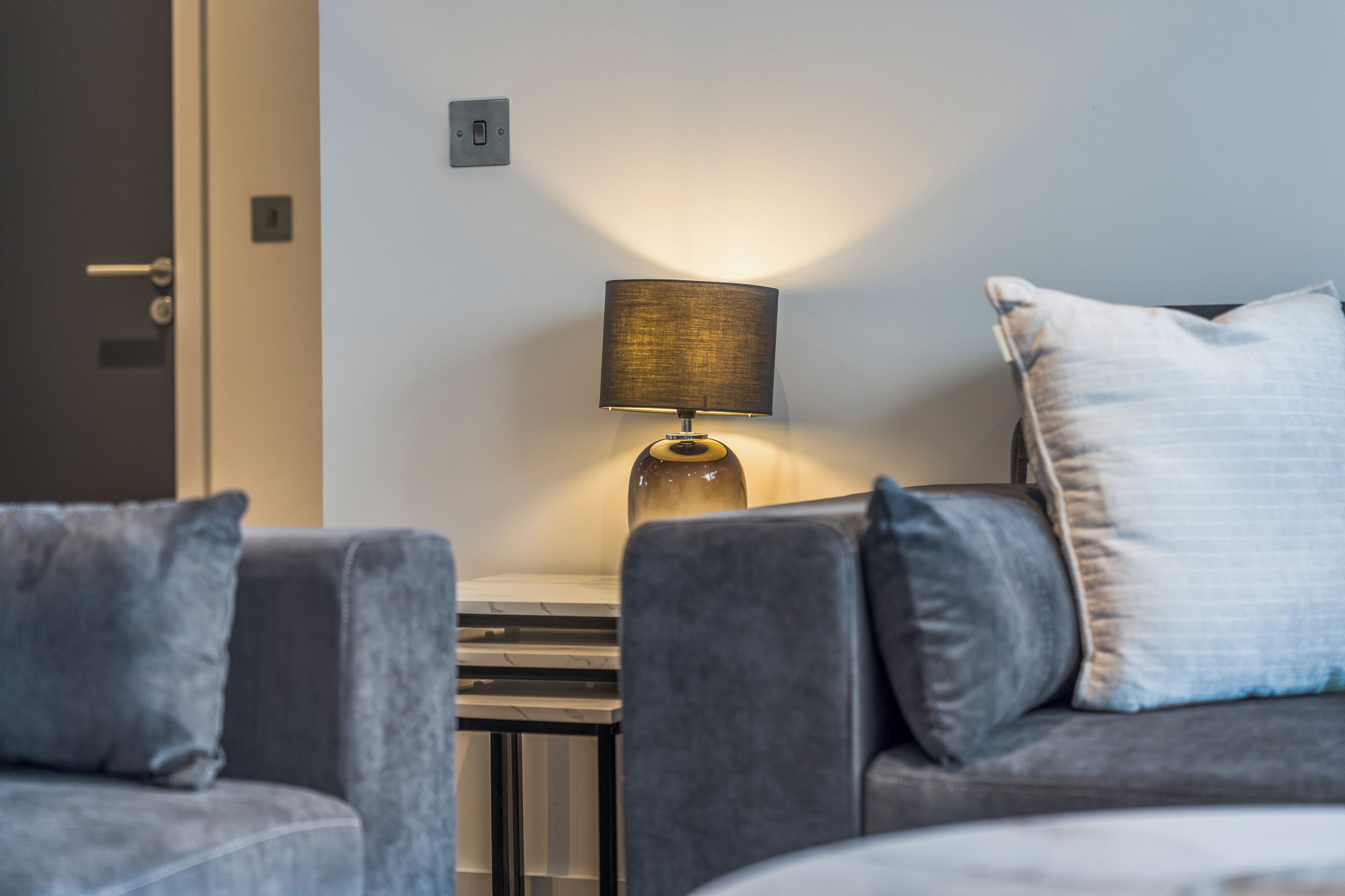 Een moderne woonkamer met een bank, een lamp en een kleine tafel.