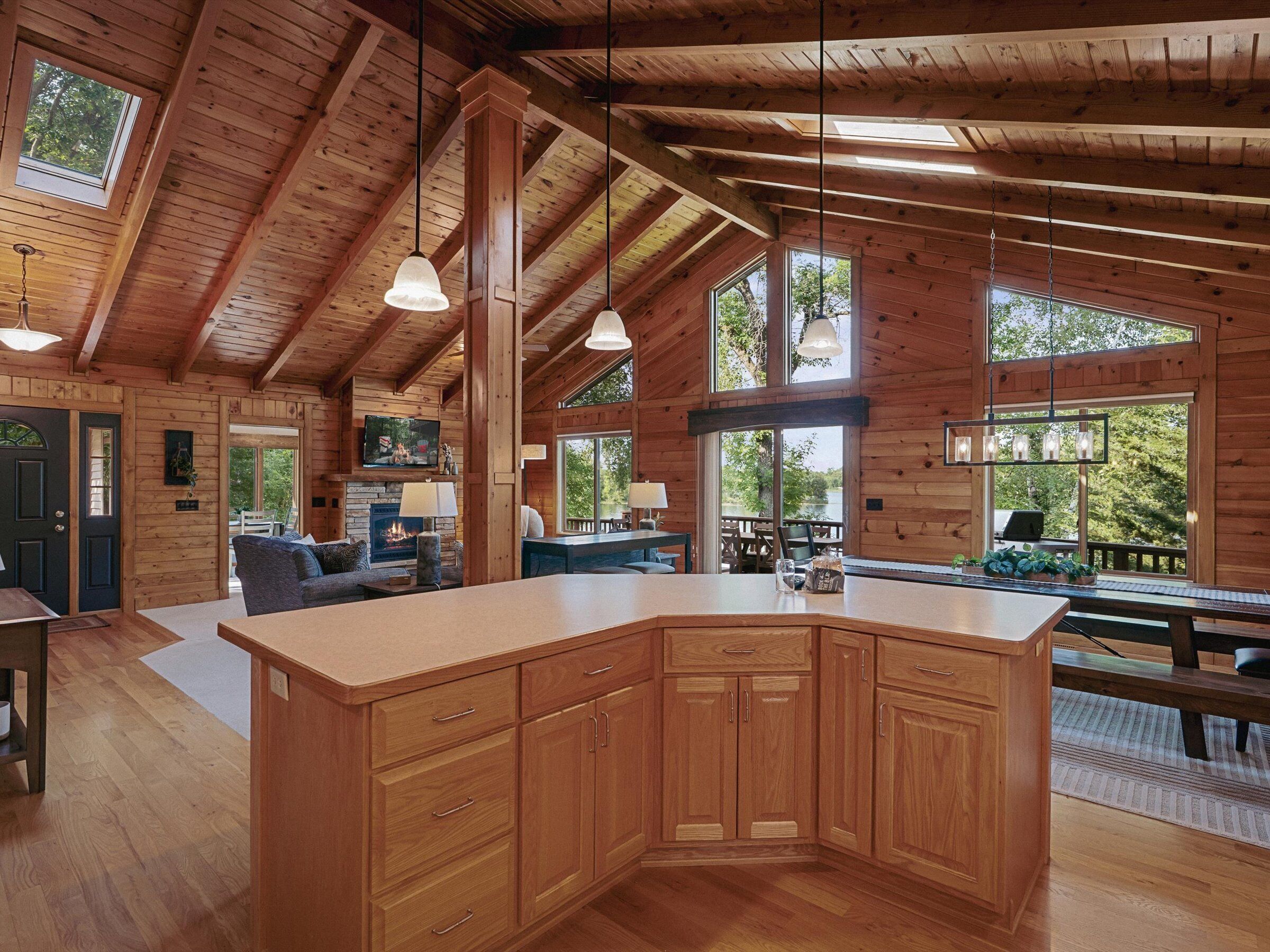 A spacious wooden cabin with a large kitchen island, multiple windows, and a cozy living area.