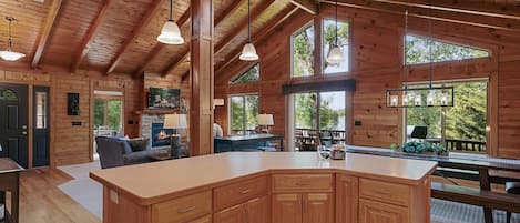 A spacious wooden cabin with a large kitchen island, multiple windows, and a cozy living area.