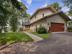 A two-story house with a garage, a front porch, and a driveway leading to the garage.