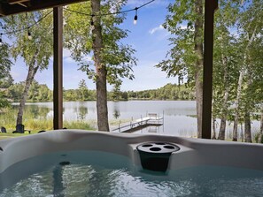 Ein Whirlpool mit Blick auf einen See und eine Anlegestelle, umgeben von Bäumen.