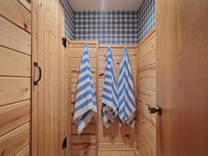 A wooden sauna with two towels hanging on hooks.