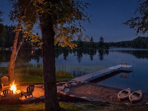 A lakeside setting with a dock, a fire pit with chairs, and kayaks. - NEW on Lake Ossie! Hot Tub | Sauna| Great Fishing (Pequot Lakes)