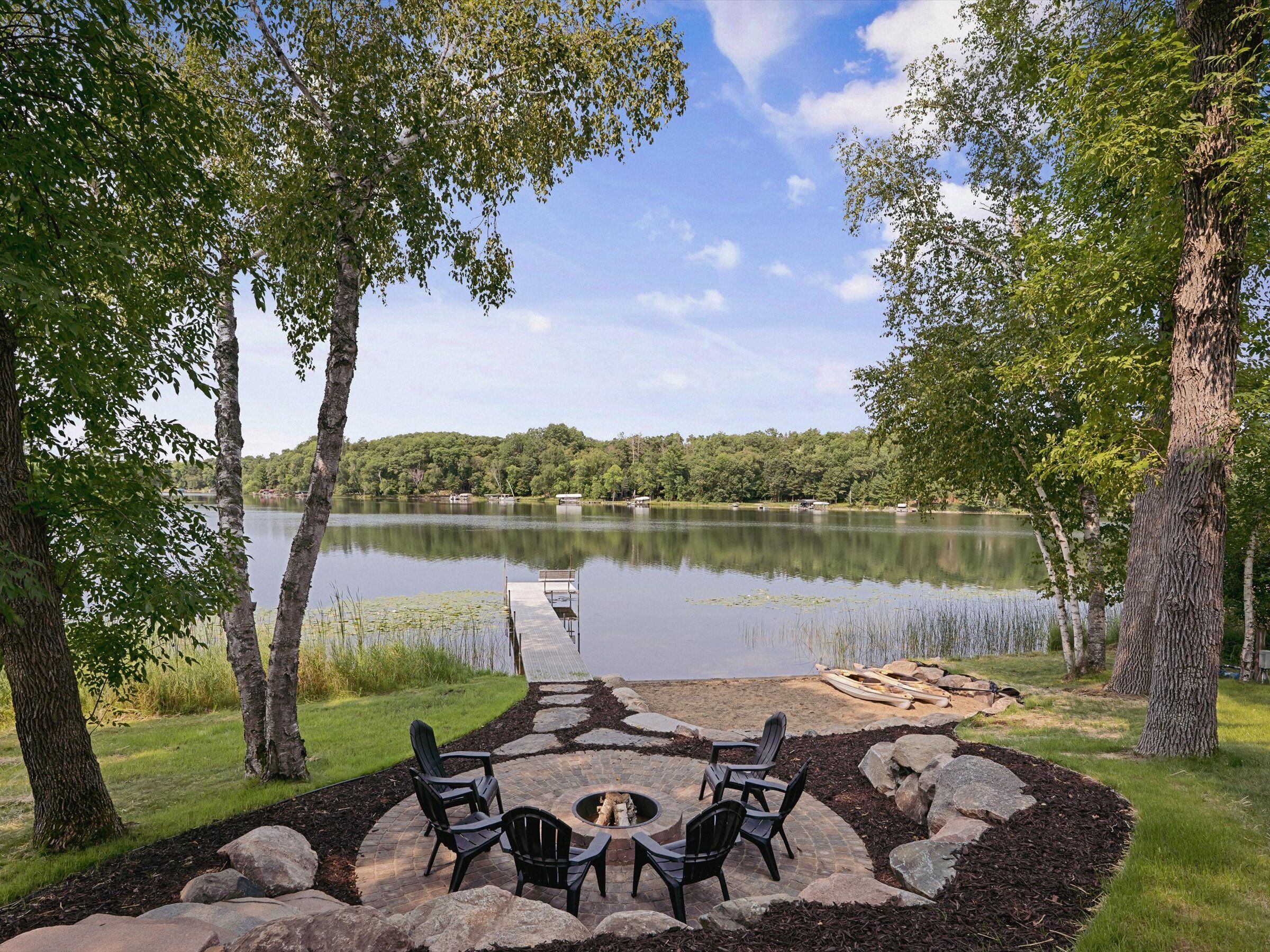 Un patio junto al lago con mobiliario exterior y una chimenea.