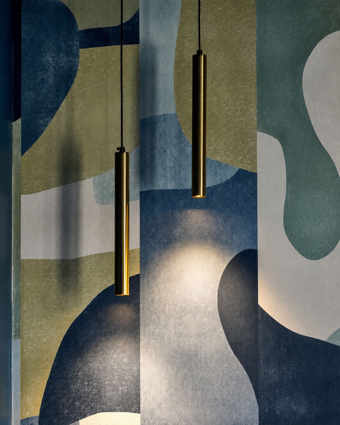Un mur orné de motifs abstraits et deux lampes suspendues.