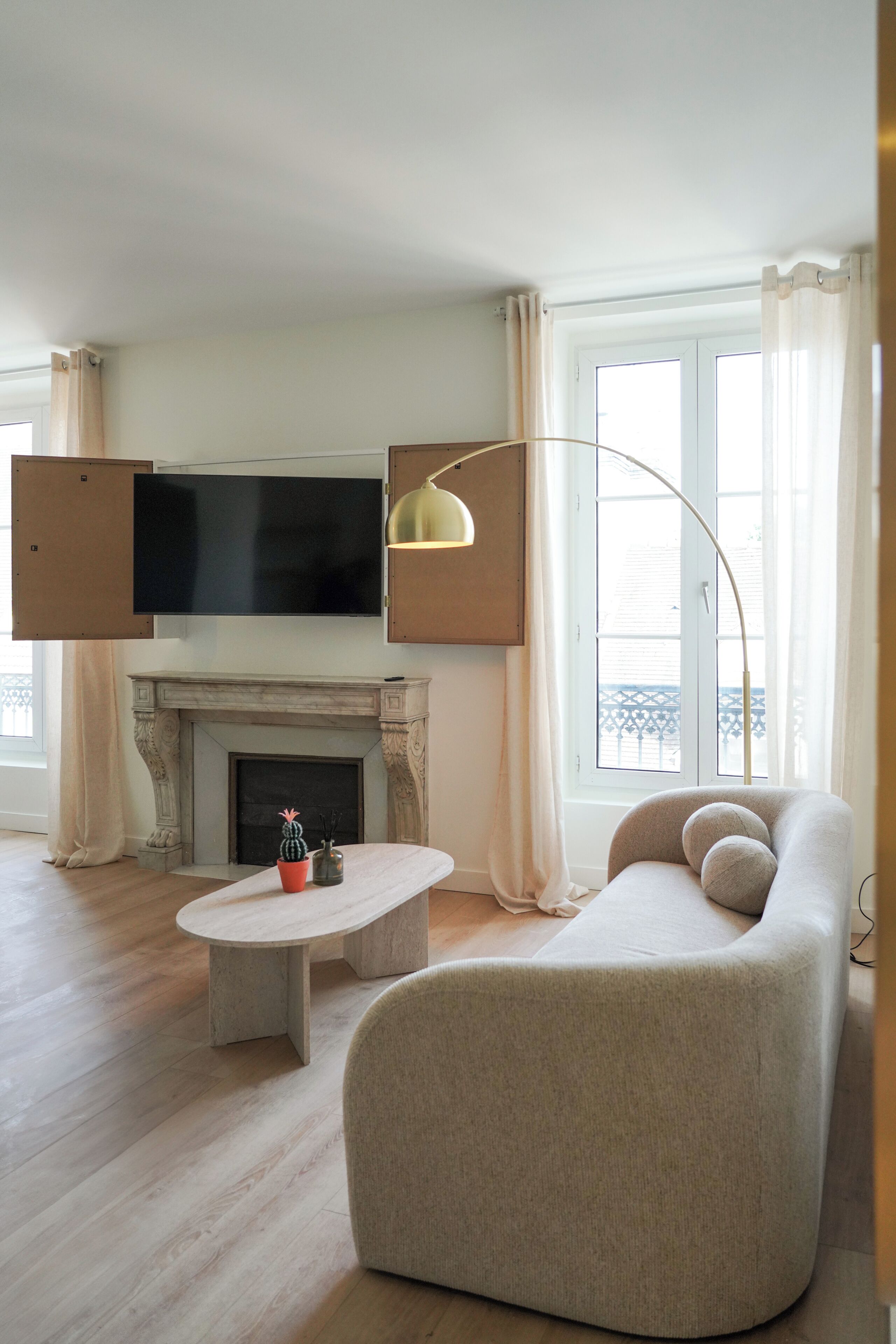A modern living room with a fireplace, a flat-screen TV mounted above it, a round coffee table with decorative items, and a comfortable sofa.