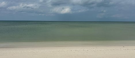 A beach with a clear view of the ocean and a sandy shore.