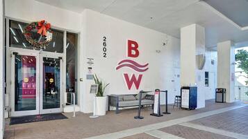 Ein Hotel Eingang mit Glastür, einem roten und weißen Schild und einer Bank davor.