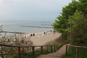 A beach with rows of beach huts and a wooden staircase leading down to the beach.