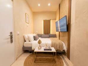 Ein modernes Schlafzimmer mit Bett, Nachttisch und einem an der Wand befestigten Fernseher.
