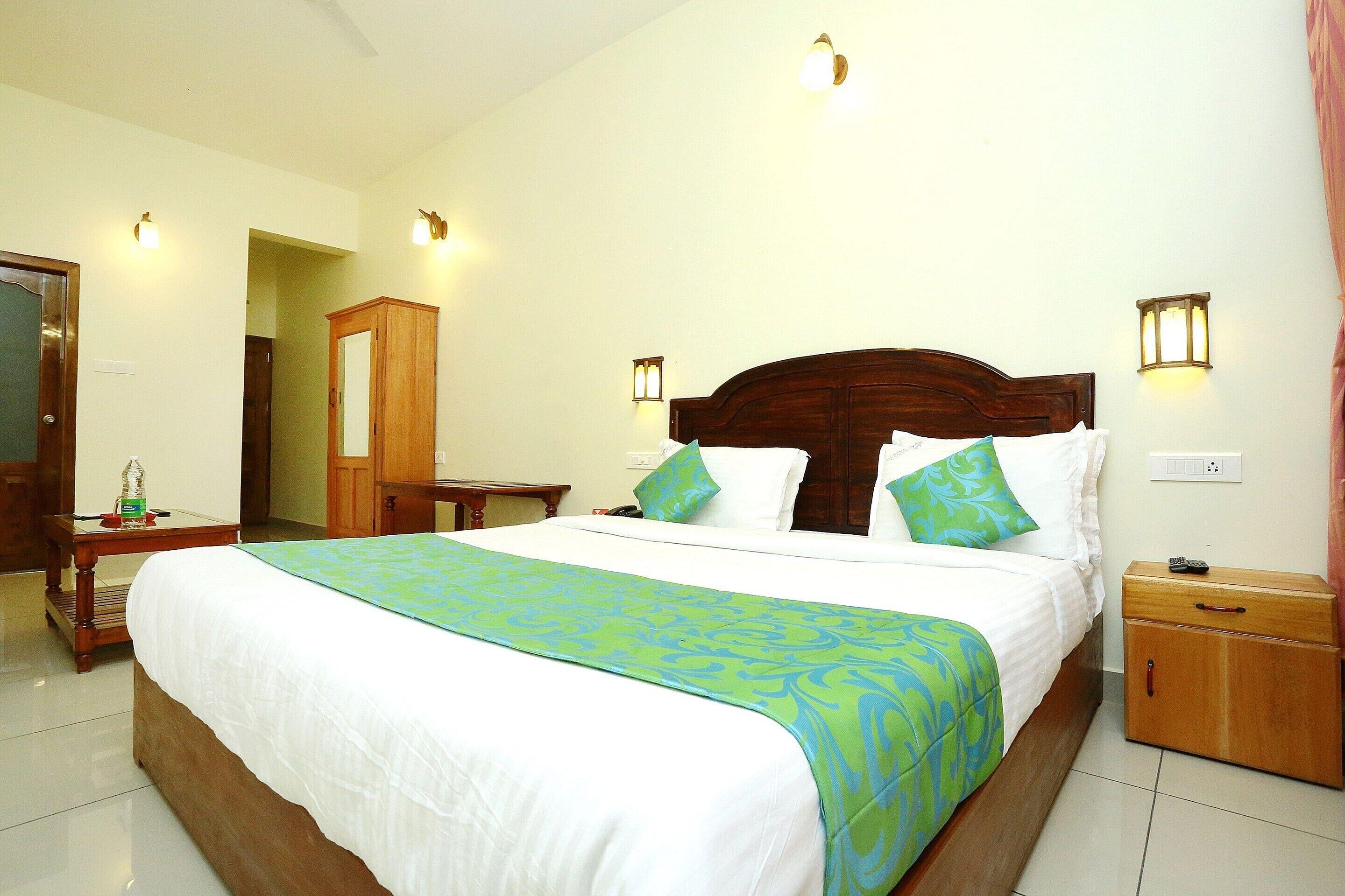A hotel room with a large bed, bedside tables, a wardrobe, and wall-mounted lighting.