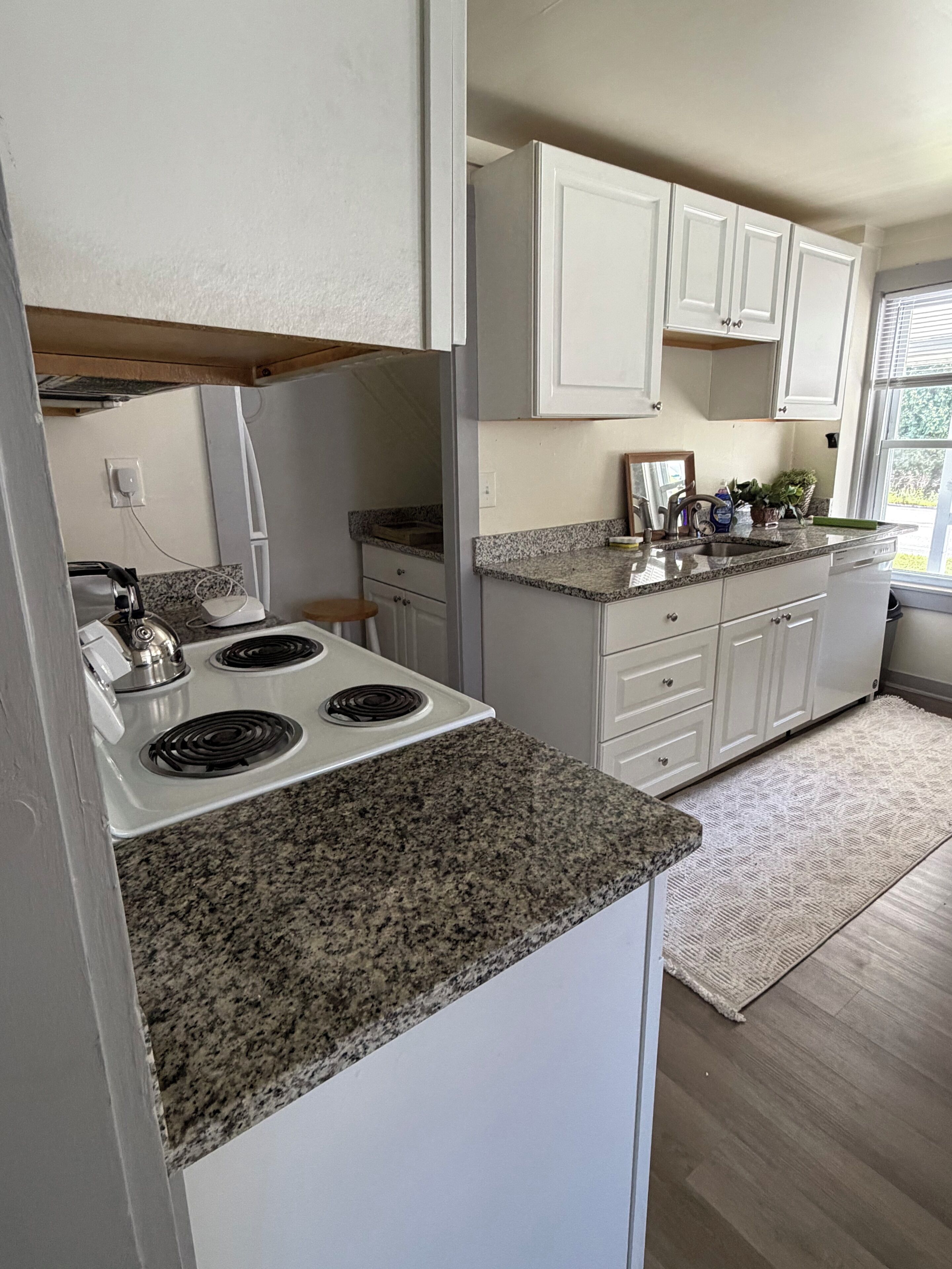 A kitchen with white cabinets, granite countertops, and a stainless steel stove.
