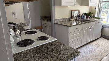 A kitchen with white cabinets, granite countertops, and a stainless steel stove.