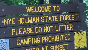 A sign welcoming visitors to Nye Holman State Forest with restrictions on littering, camping, and picnicking.