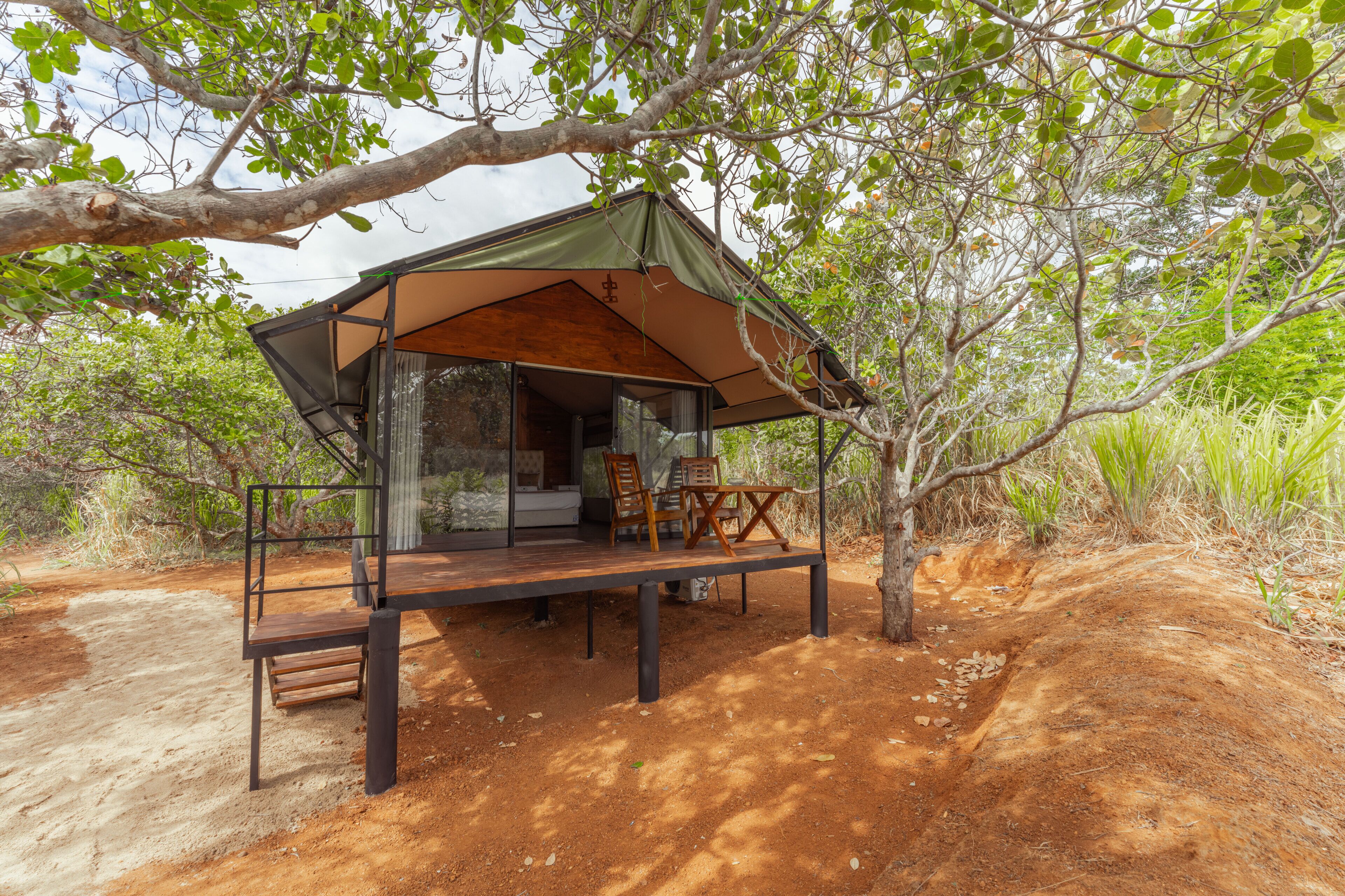 A treehouse with a wooden deck and a single bed.