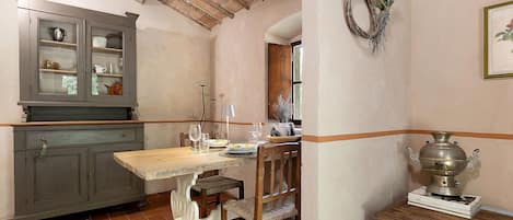 A rustic kitchen with a wooden table, chairs, a cabinet, and a wall-mounted decoration.