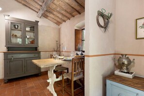 A rustic kitchen with a wooden table, chairs, a cabinet, and a wall-mounted decoration.