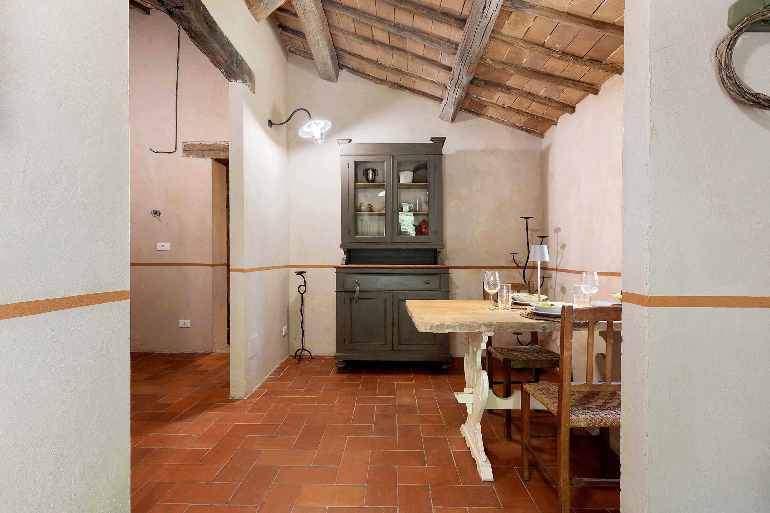 Una cucina rustica con un tavolo di legno, un armadietto e una lampada a sospensione.