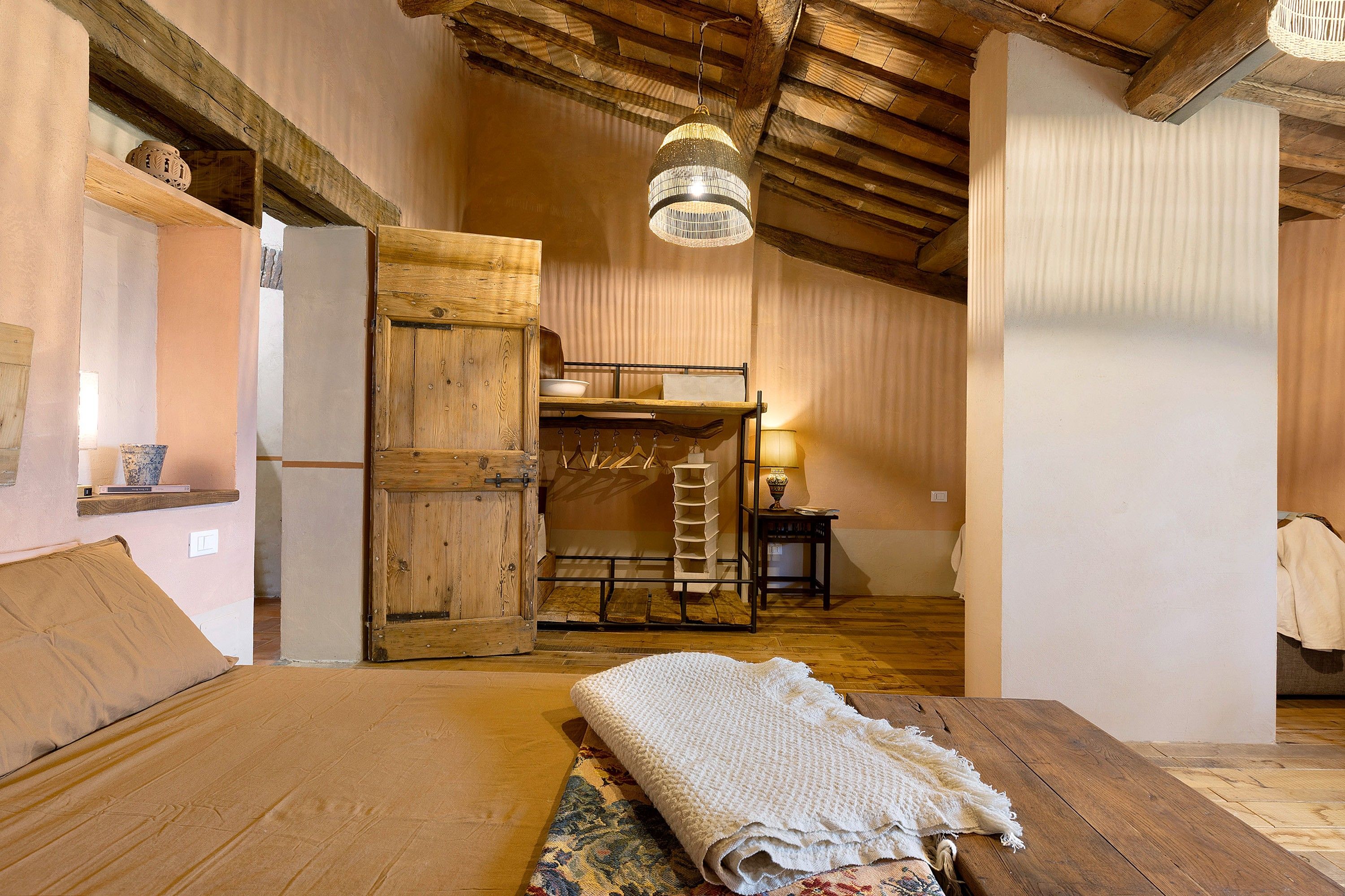 Une chambre rustique avec un lit superposé en bois, un luminaire suspendu et un tapis à motifs.