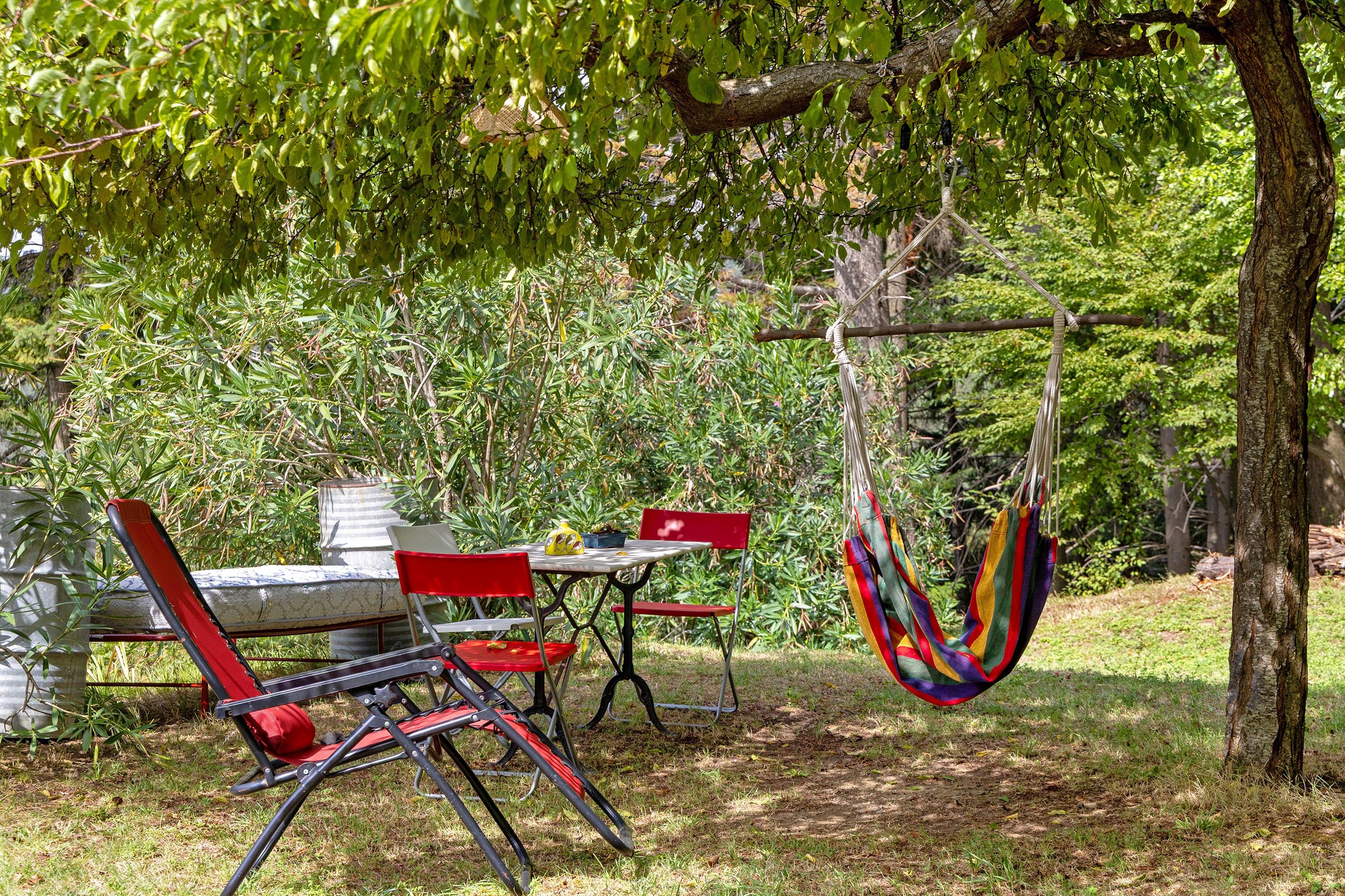 An outdoor seating area with a table and chairs, a hammock, and a tree.