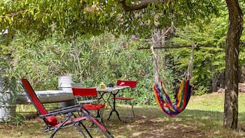 An outdoor seating area with a table and chairs, a hammock, and a tree.