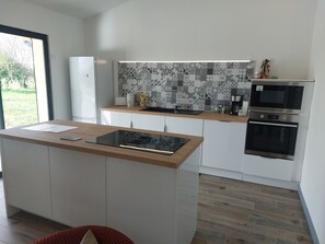 A modern kitchen with a central island, built-in oven, and a patterned backsplash. - Château le Mas Vacation Rental with Pool: Ideal for Families, a Haven of Peace in the Castle Grounds (ST MARTIAL D ARTENSET)