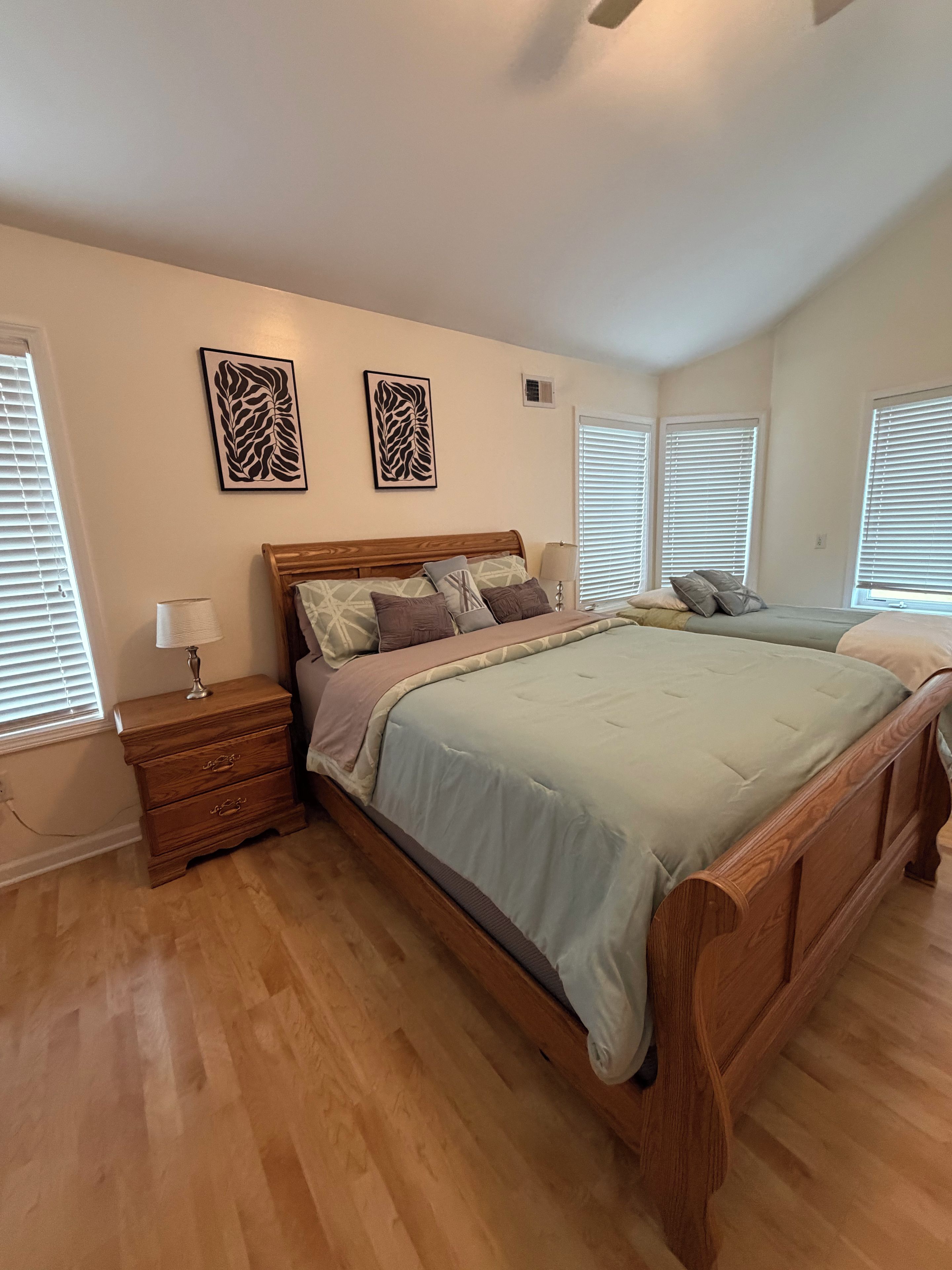 Une chambre à coucher avec un lit en bois, des tables de chevet et des œuvres d’art murales.