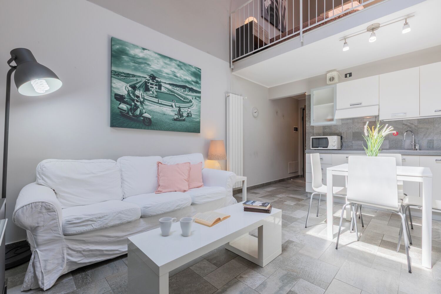 Een moderne woonkamer met een witte bank, een salontafel en een schilderij van een scooter aan de muur.