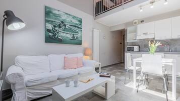 Un salon moderne avec un canapé blanc, une table basse et un tableau représentant une moto sur le mur.