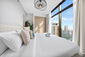 Habitación de hotel moderna con una cama grande, vistas a la ciudad y una lámpara de techo original.