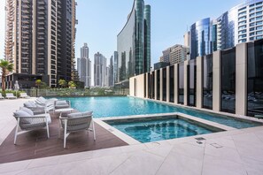 A rooftop pool with lounge chairs and a cityscape view. - StayShort - 2 Bedroom in Business Bay Sleeps 6 with Water Canal Views! (Business Bay)