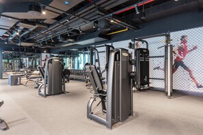 Un gimnasio con diversos equipos de ejercicio, incluyendo máquinas de pesas y pesas libres.