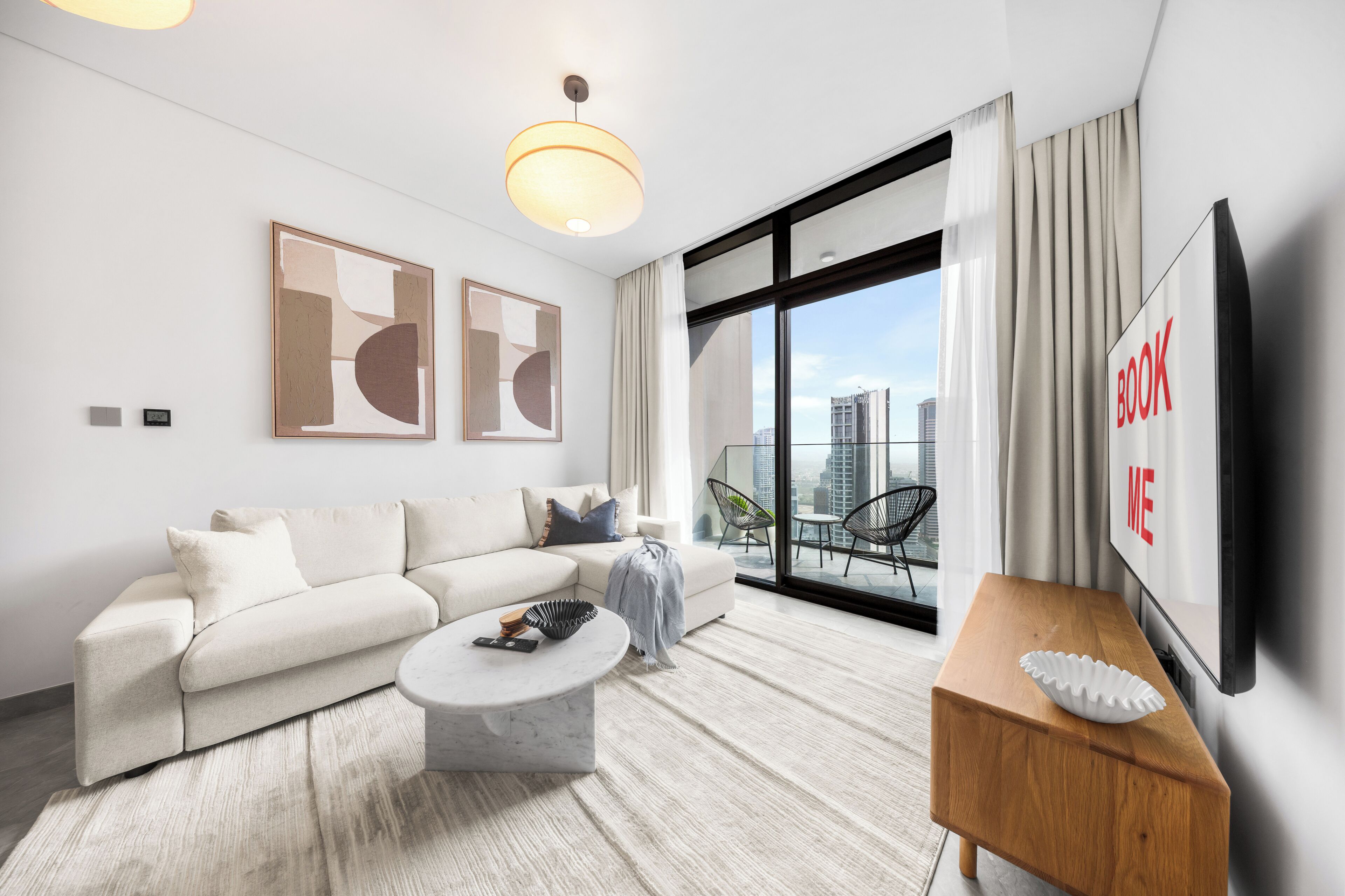 A modern living room with a sofa, coffee table, and a view of the city through large windows.