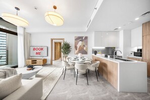 A modern kitchen with a central island, dining area with chairs, and a living space with a sofa and a coffee table.