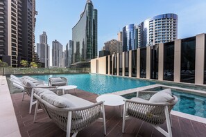 A rooftop pool with lounge chairs and a city skyline in the background.