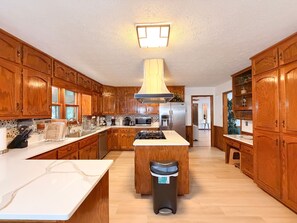 A kitchen with wooden cabinets, a central island, a stainless steel refrigerator, and a microwave.