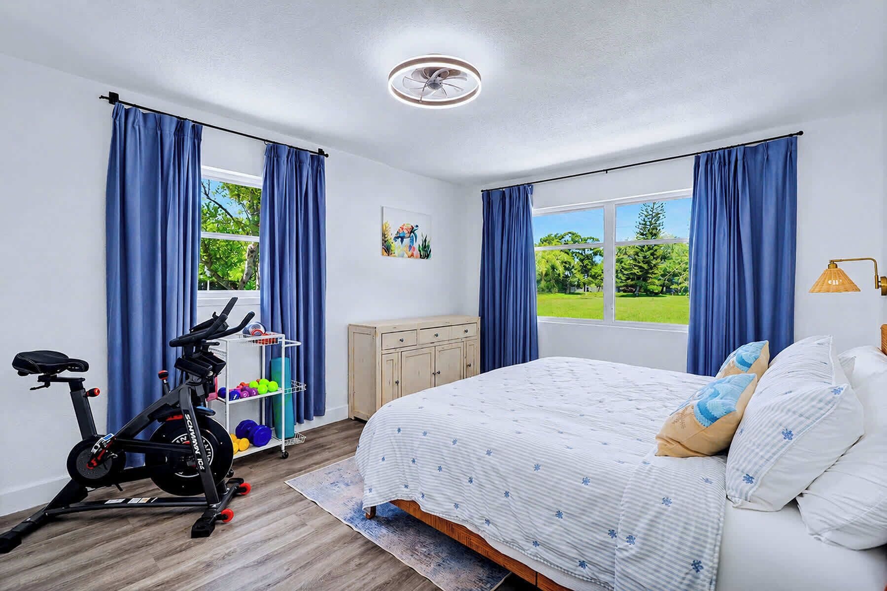 Quarto com cama, bicicleta de exercícios e vista para uma paisagem verde.